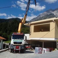 Lkw-Kran lädt ein Holzhaus ab